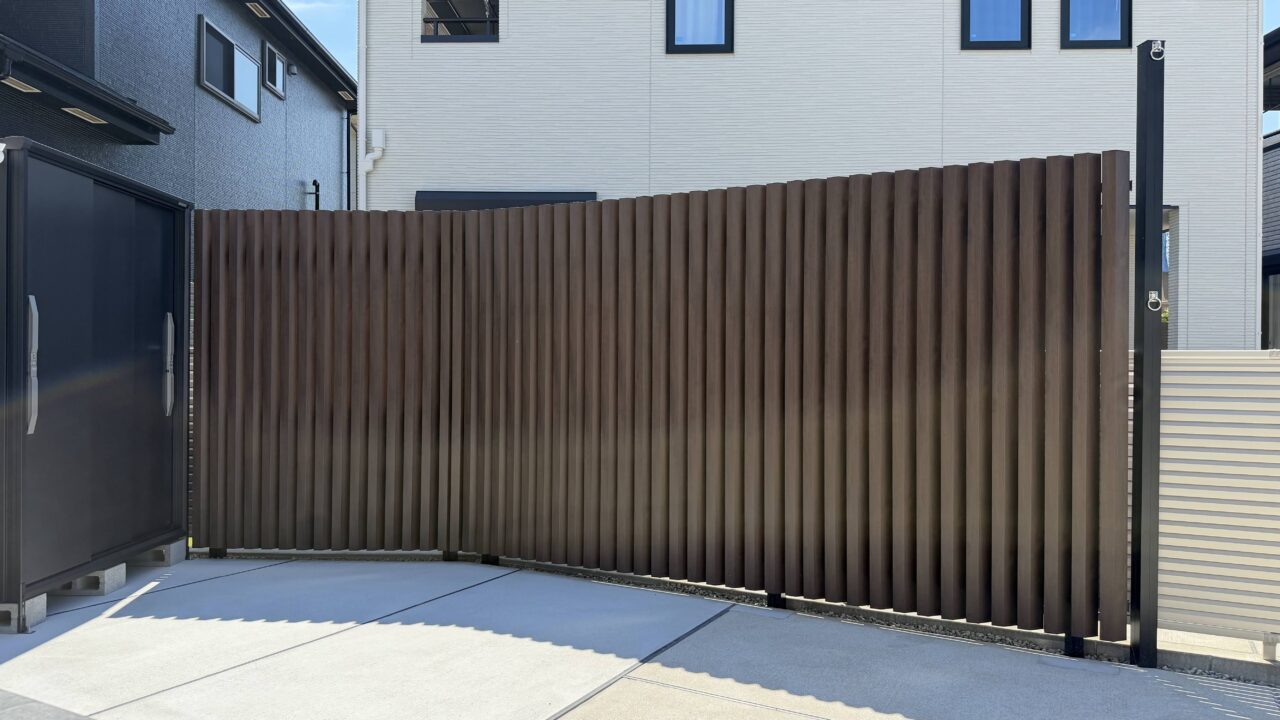 福岡市東区のお庭リフォームで設置した、三協アルミのスクリーンフェンス「エルファードM5型」。お庭からの景観を重視した木調色（トラッドオーク×ブラック）で、光と風を通しながら視線を遮る角度格子を採用しています。