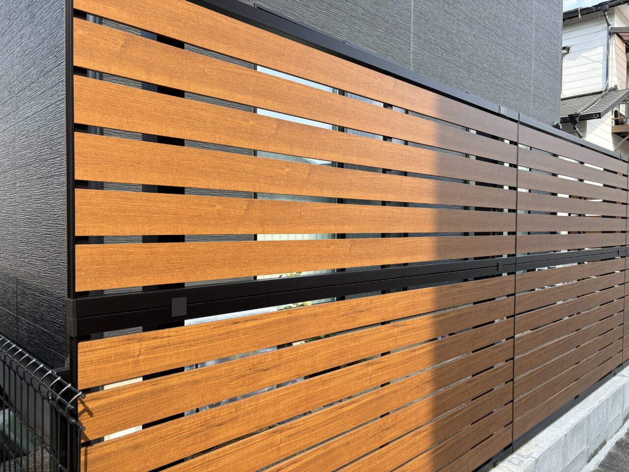 福岡市東区で設置したYKKルシアスフェンスYS2H型（キャラメルチーク×カームブラック）の木調フェンスディテール写真｜ウェルミカ