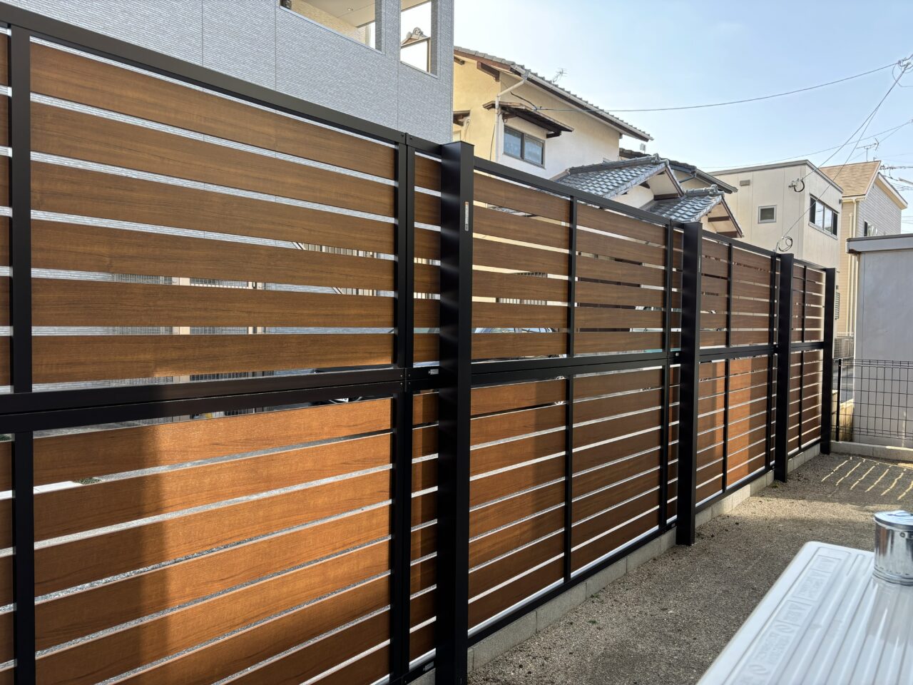 福岡市東区で施工したYKKルシアスフェンスYS2H型（キャラメルチーク×カームブラック）の内側から見た木調フェンスの様子｜ウェルミカ