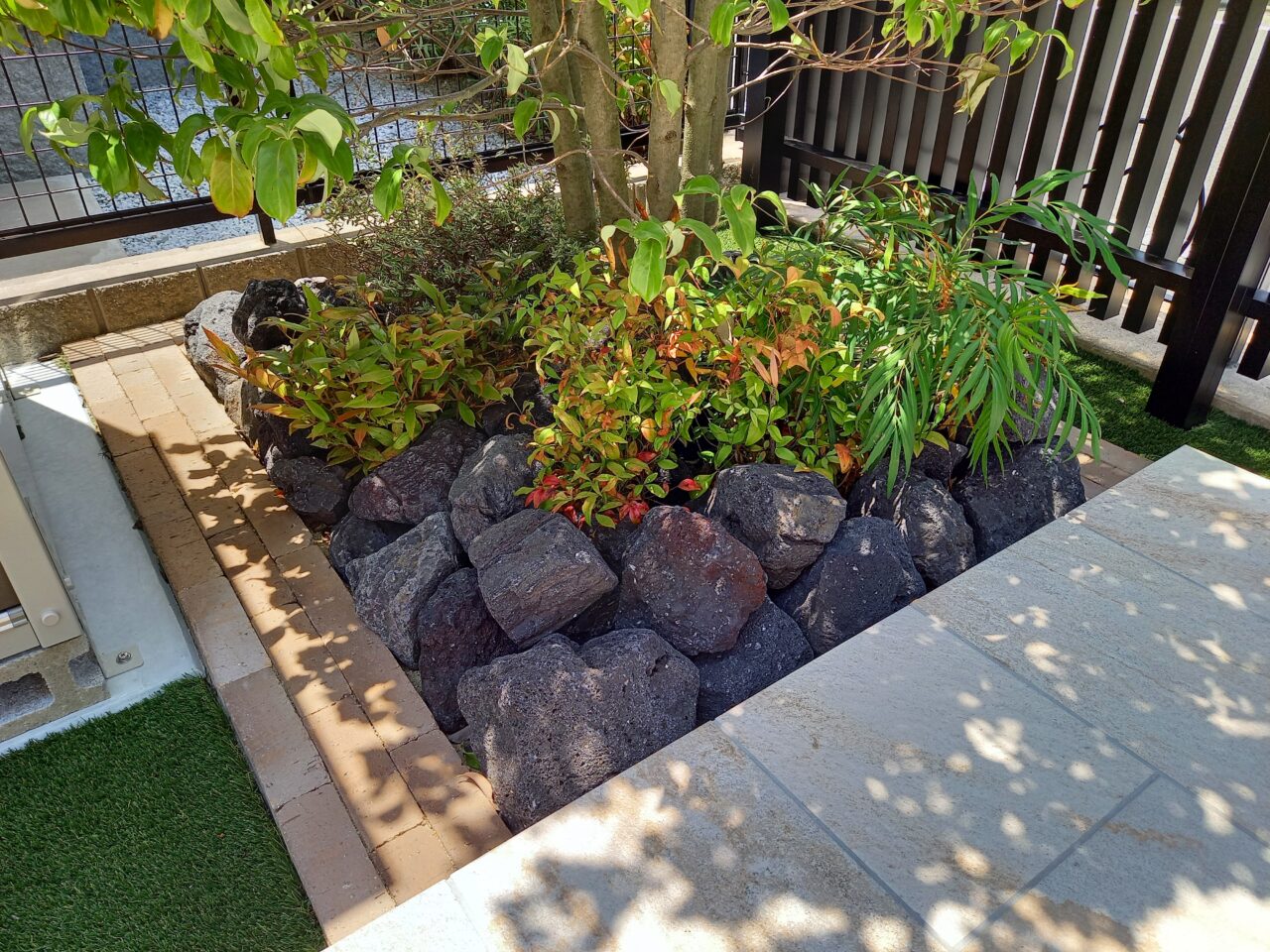 福岡県北九州市小倉南区の外構リフォームで施工した造作花壇。東洋工業「バロンブリックボーダー」と「クラッシュロック ボルカブラック」を使用し、植栽の緑が映える上質なデザインに仕上げました。