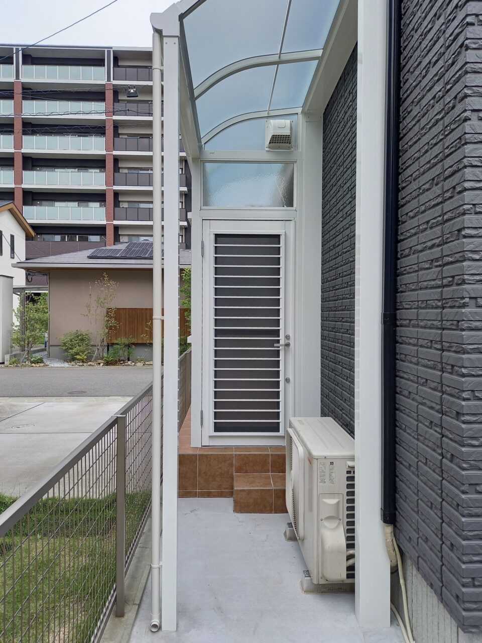 北九州市戸畑区の外構リフォームで設置したサンルームのお庭側出入口。ワンステップ階段とテラス屋根で、雨の日も出入りしやすい動線設計