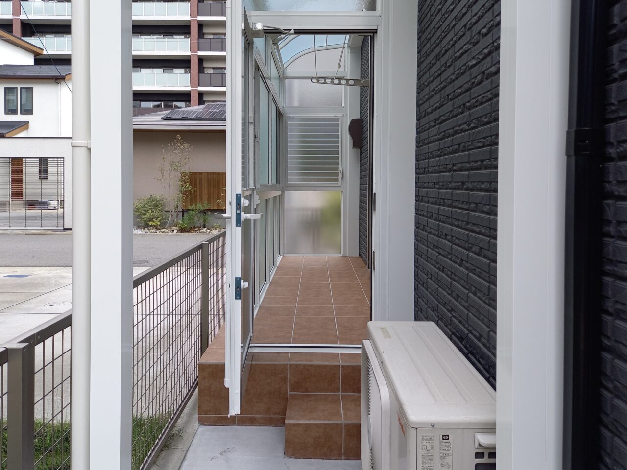 サンルーム出入口に設けたワンステップ階段。リビングからの出入りがしやすい、家事動線に配慮した外構リフォーム