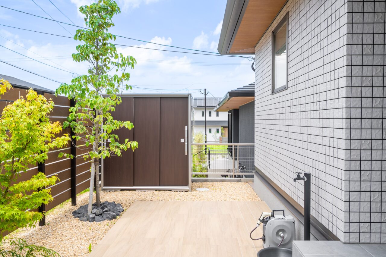 岡垣町で施工した外構リフォームの完成写真｜人工木フェンスと木目調タイルデッキ、植栽が調和した落ち着きのあるプライベートガーデン｜ウェルミカ