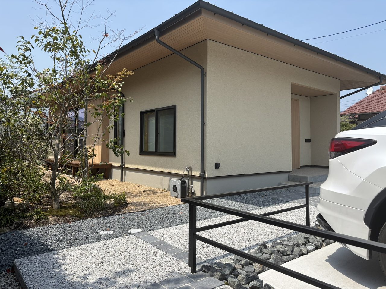 洗い出し仕上げのアプローチとブラックのフレームフェンスが、建物の外観と美しく調和するシンプル和モダンなファサード空間。